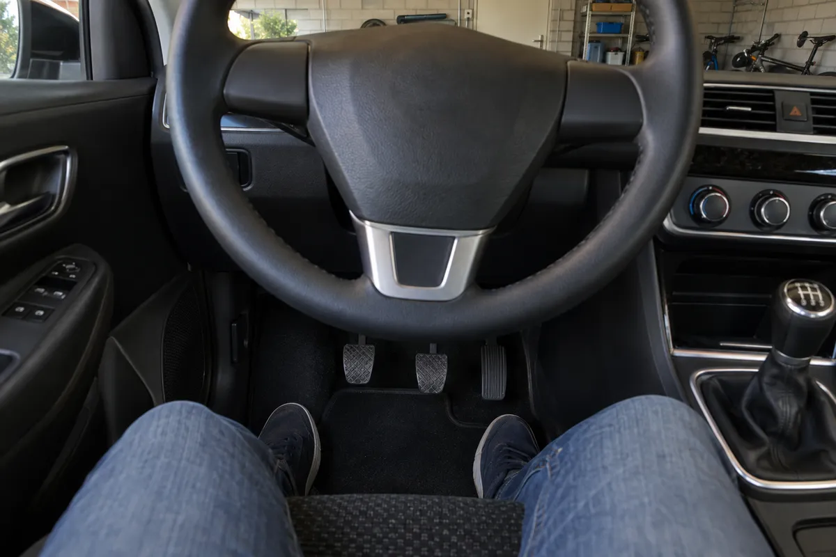 Het stuur en de pedalen van een stilstaande auto, vóór het controleren van de rembediening.