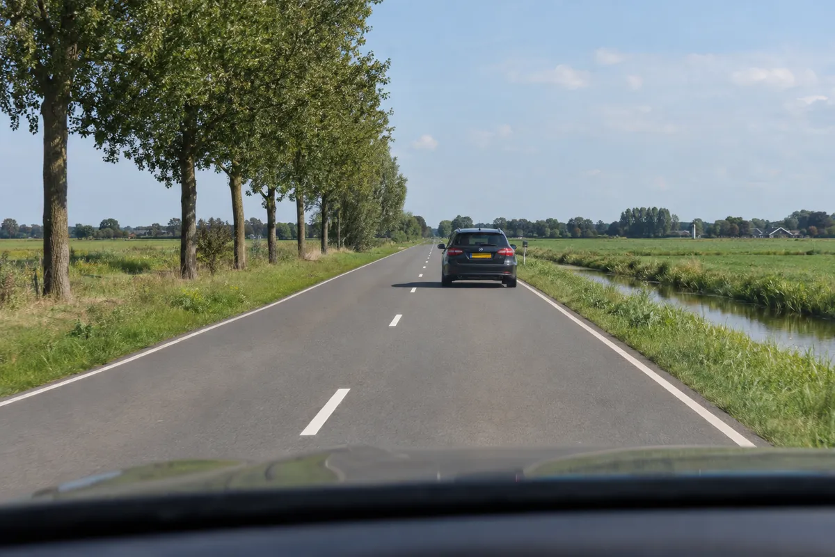 Vanuit de bestuurdersplaats zie je een auto op voldoende afstand voor je in dezelfde rechterrijstrook.