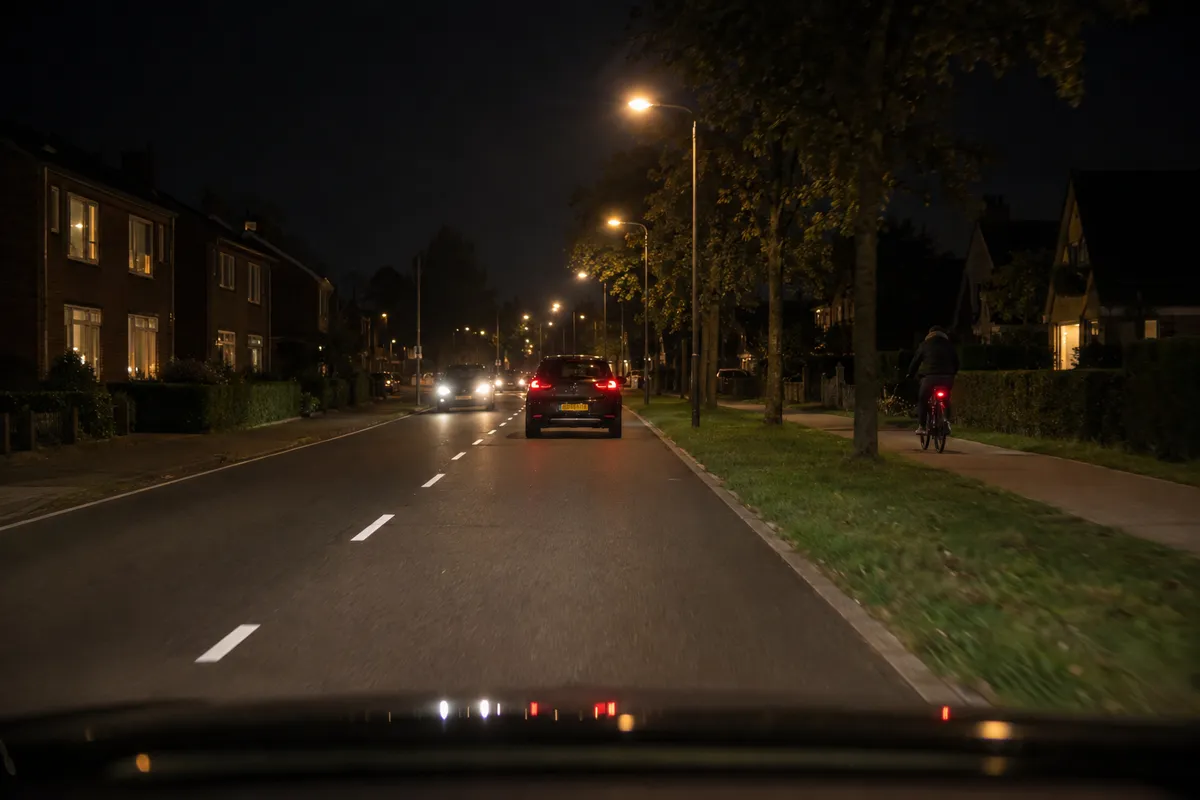 Een fietser van achteren op een pad naast de weg, met een rood achterlicht.