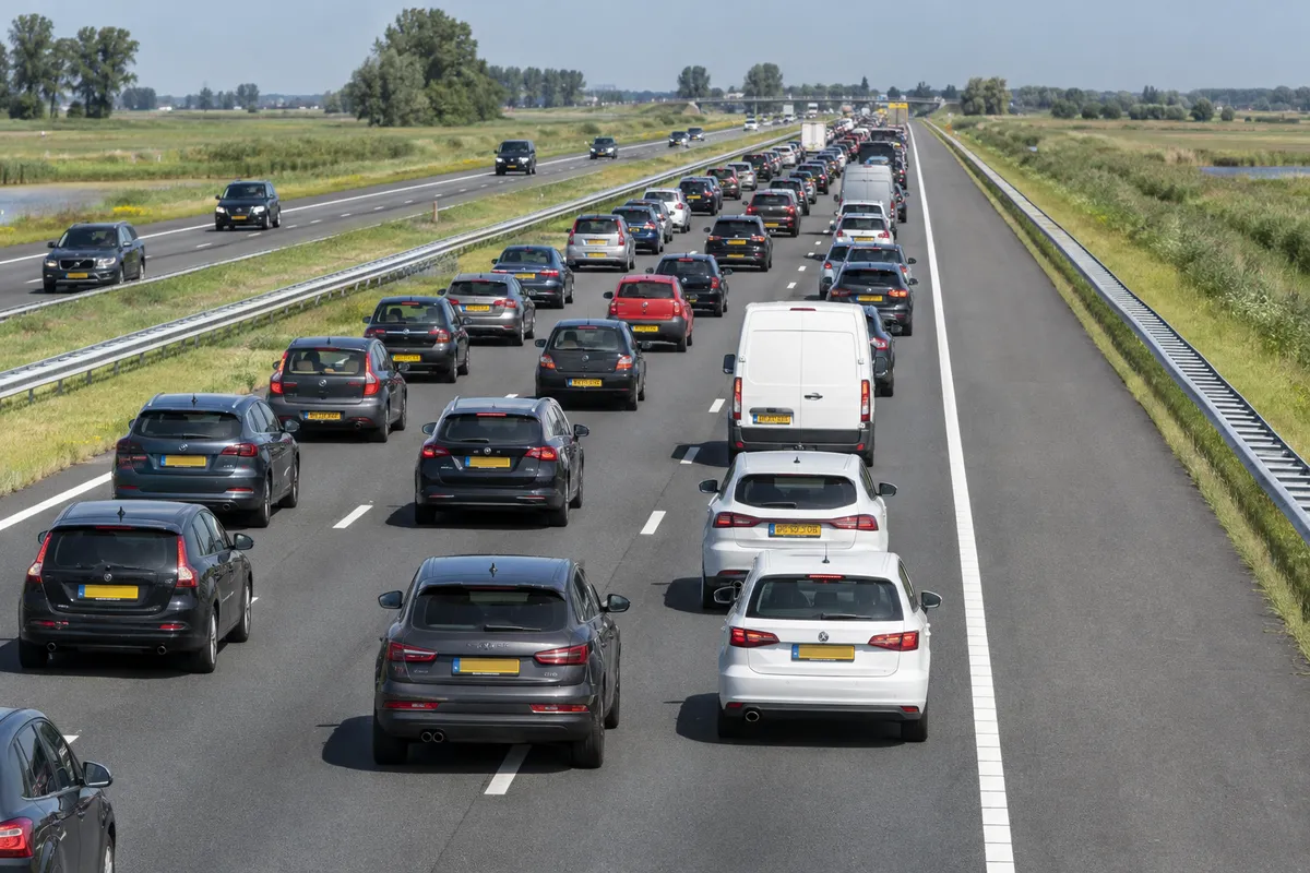 Foto van bovenaf op een autosnelweg: stilstaand verkeer op de rijstroken en rechts een lege vluchtstrook, afgescheiden door een doorgetrokken streep