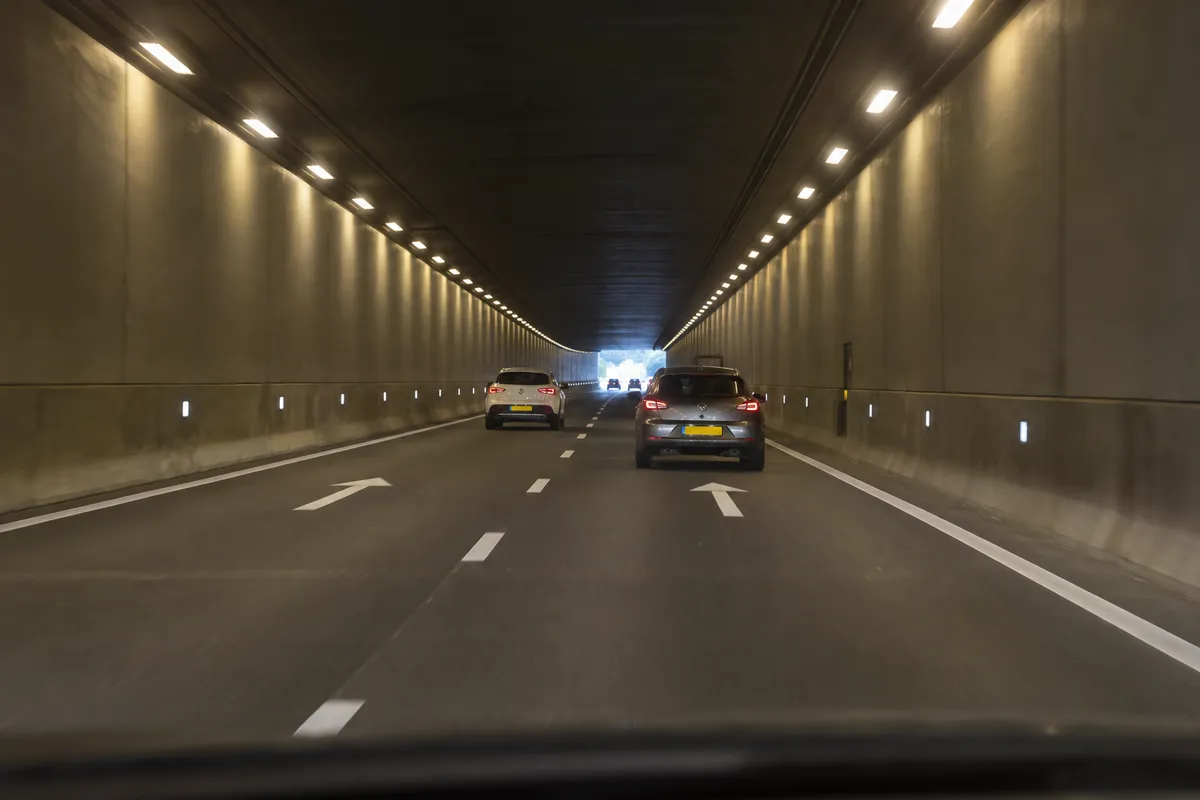 Je rijdt nog midden op de rechterrijstrook in de tunnel, de uitgang ver voor je.