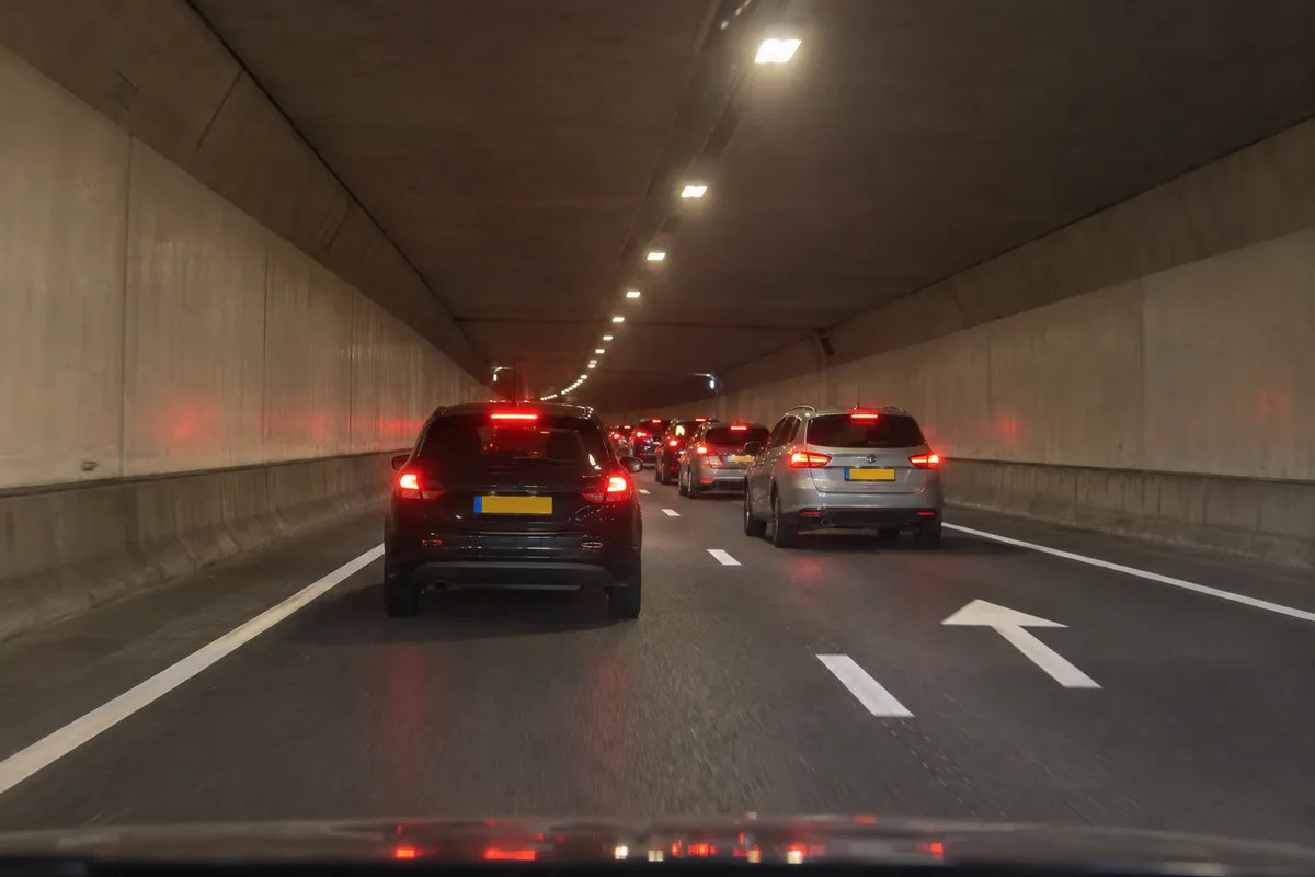 Je nadert in de tunnel het einde van een rij auto's die verderop langzamer rijden.