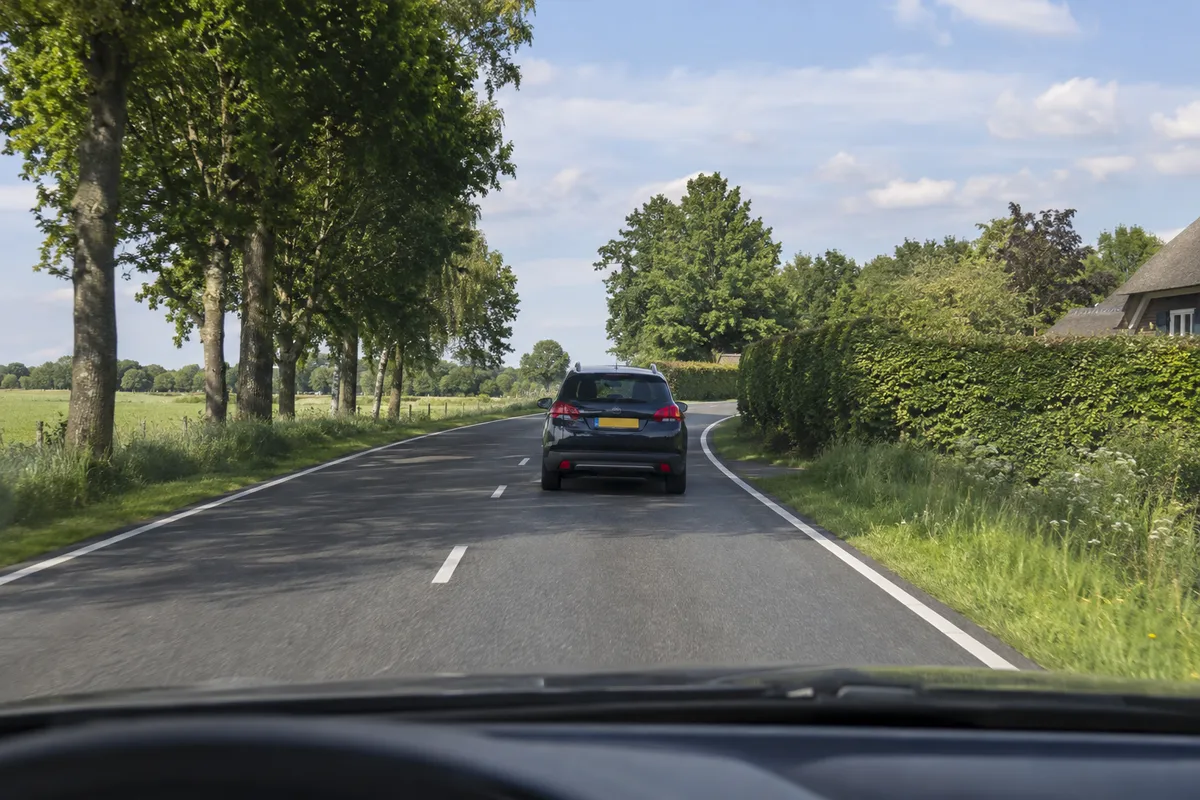 Je volgt een auto naar een bocht die het zicht op de weg beperkt.