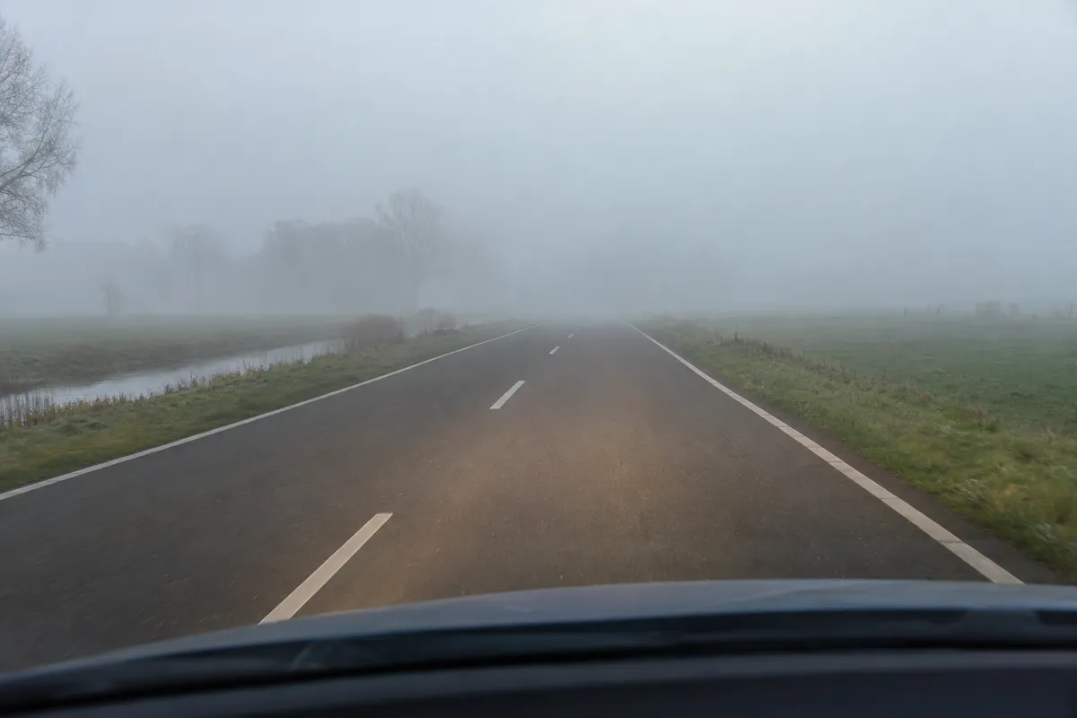 De weg verdwijnt verderop in mist; het zichtbare deel is vrij.