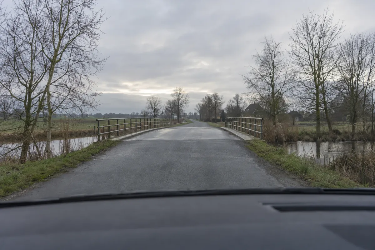 Je nadert een brug op een koude, vochtige ochtend.