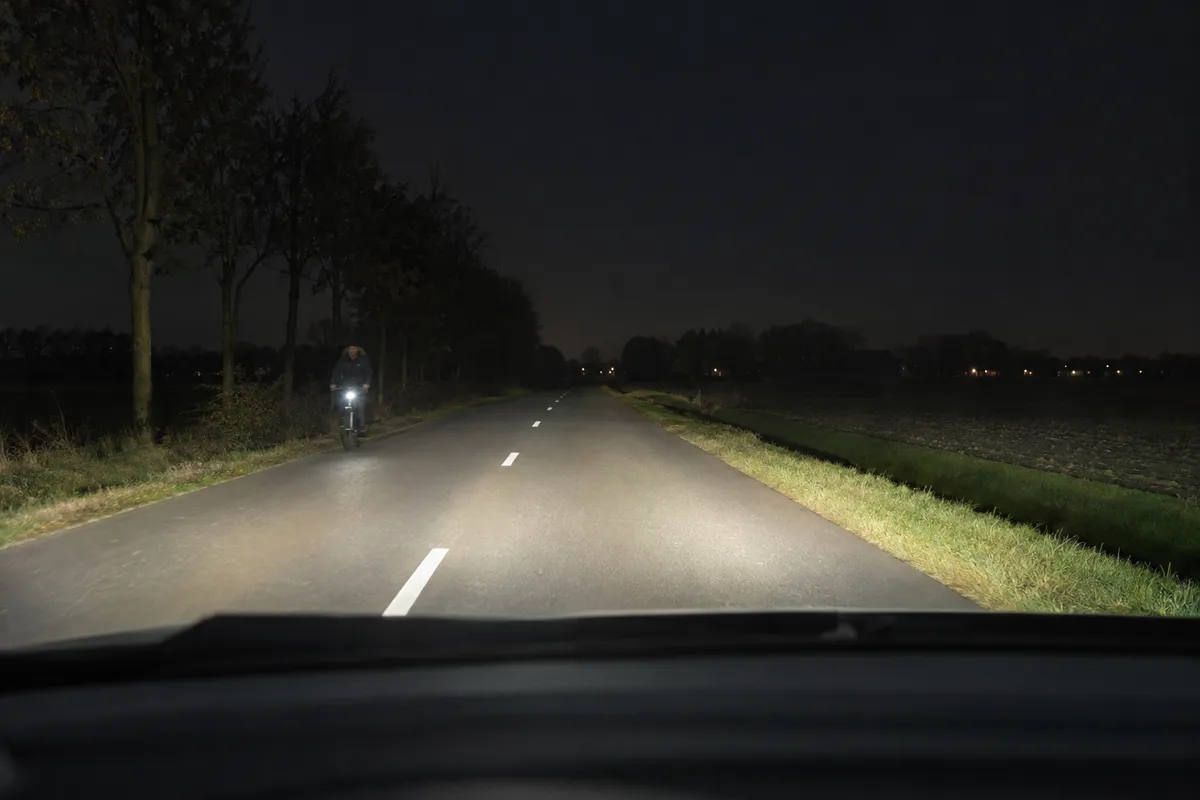 Op een donkere weg komt een fietser je tegemoet.